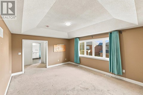 A spacious room with a carpeted floor and a large window with green curtains.