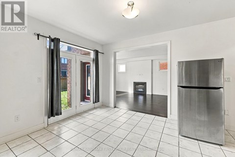 A white tiled kitchen with a refrigerator and a door leading outside.