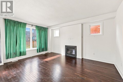 A spacious room with a fireplace and a window with green curtains.
