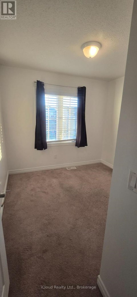 A room with a carpeted floor and a window with black curtains.