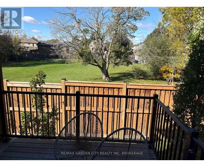 A deck with a railing and a view of a yard and houses.