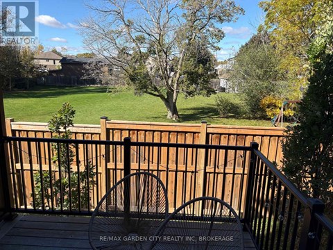 A deck with a railing and a view of a yard and houses.