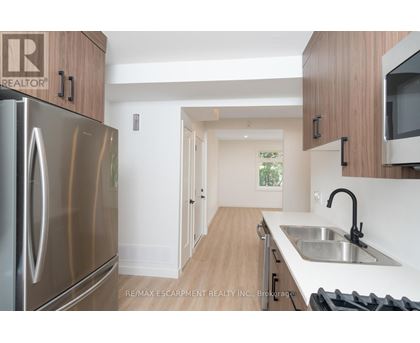 A kitchen with a stainless steel refrigerator and wooden cabinets.