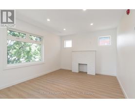 A white fireplace in a room with wooden floors and a window.