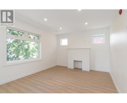 A white fireplace in a room with wooden floors and a window.