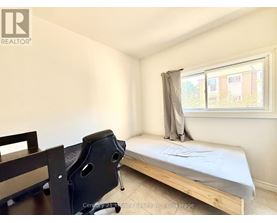 A bedroom with a bed, chair, and window.