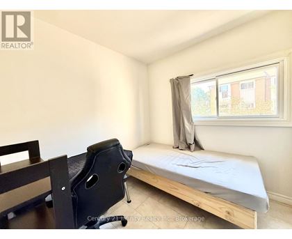 A bedroom with a bed, chair, and window.