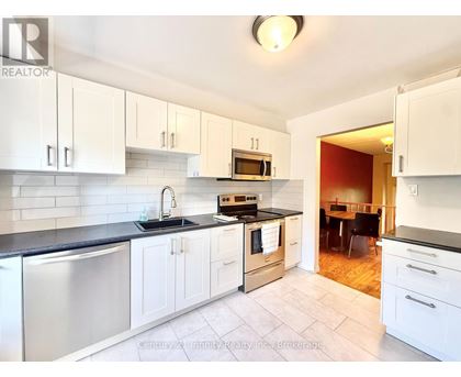 A kitchen with white cabinets and a black counter top.