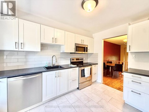 A kitchen with white cabinets and a black counter top.