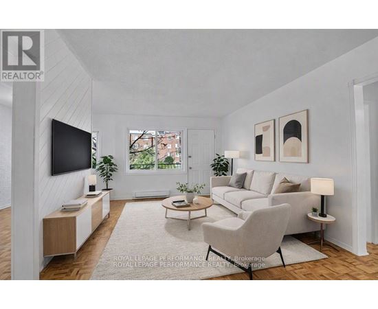 A living room with a grey couch, a white chair, a television, and a window.