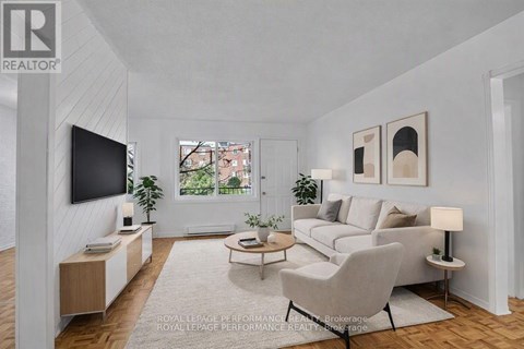 A living room with a grey couch, a white chair, a television, and a window.