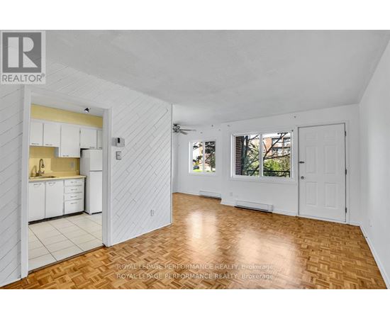 A spacious room with wooden flooring and white walls.