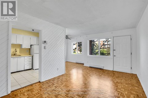 A spacious room with wooden flooring and white walls.