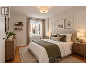 A bedroom with a large bed, a nightstand with a lamp, and a window with a view of a building outside.