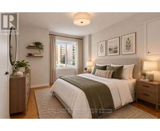 A bedroom with a large bed, a nightstand with a lamp, and a window with a view of a building outside.