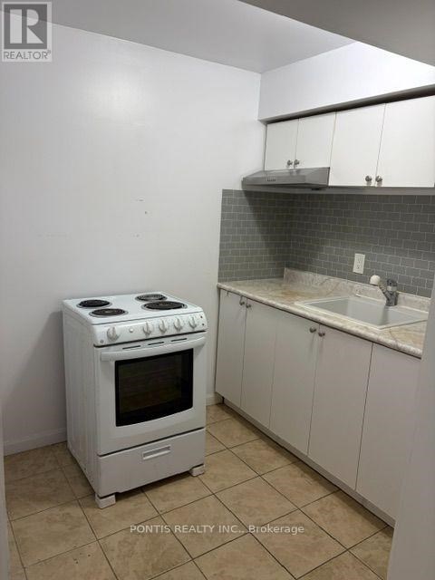 A white stove and oven in a kitchen with white cabinets and a tiled backsplash.