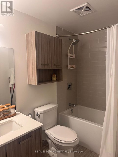 A white toilet sits in a bathroom with a white tub and a white shower curtain.