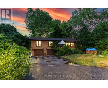 A house with a driveway and a sunset in the background.