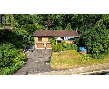 A house with a driveway and a garage is surrounded by greenery.