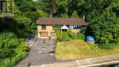 A house with a driveway and a garage is surrounded by greenery.