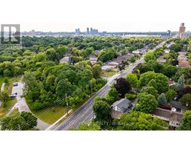 A bird's eye view of a residential area with houses, trees, and a road.