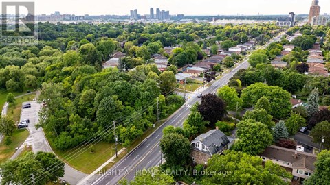 A bird's eye view of a residential area with houses, trees, and a road.