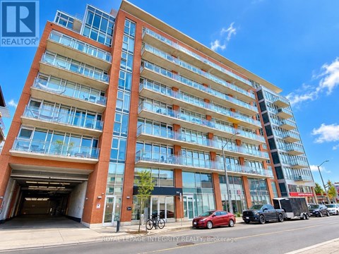 A tall building with a glass facade and a red car parked in front.
