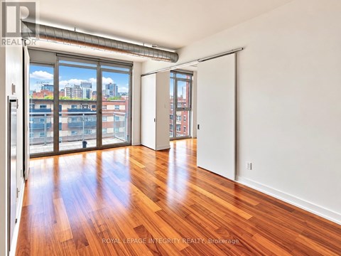 A room with wooden floors and a view of the city through the windows.
