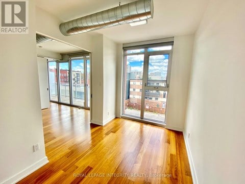 A room with wooden floors and a large window overlooking a cityscape.