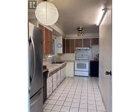 A kitchen with white tiled floors and a black refrigerator.