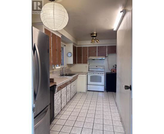A kitchen with white tiled floors and a black refrigerator.