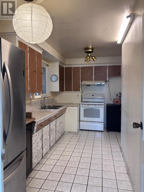 A kitchen with white tiled floors and a black refrigerator.