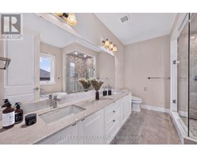 A bathroom with a large mirror, double sinks, and a walk-in shower.