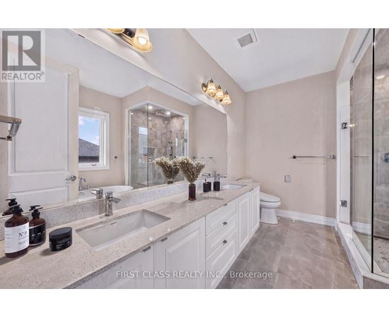 A bathroom with a large mirror, double sinks, and a walk-in shower.