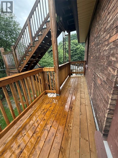 A wooden deck with a staircase leading to a balcony.