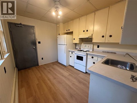 A kitchen with a sink, refrigerator, and oven.