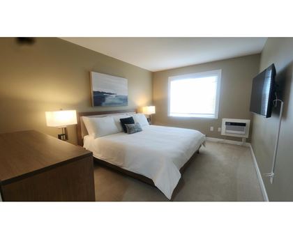 A bedroom with a bed, nightstand, and lamp.
