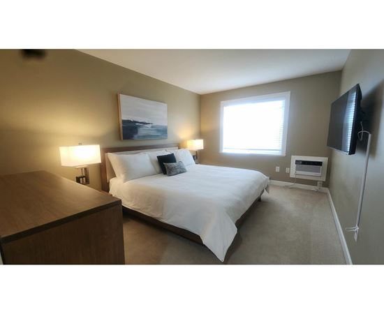 A bedroom with a bed, nightstand, and lamp.