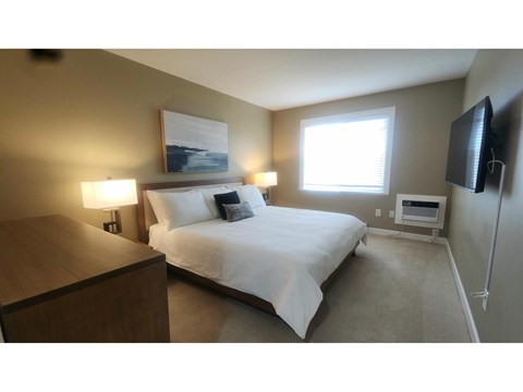 A bedroom with a bed, nightstand, and lamp.