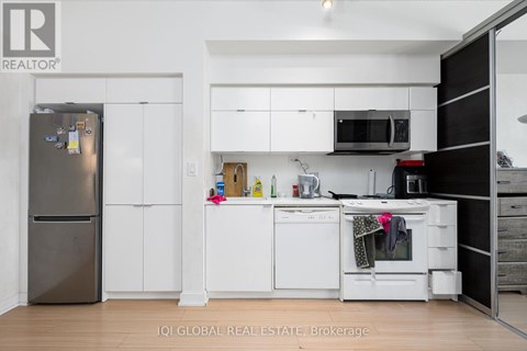 A kitchen with white cabinets and a black fridge.