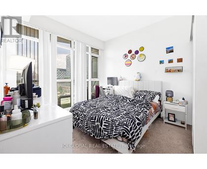 A bedroom with a large bed and a window overlooking a cityscape.