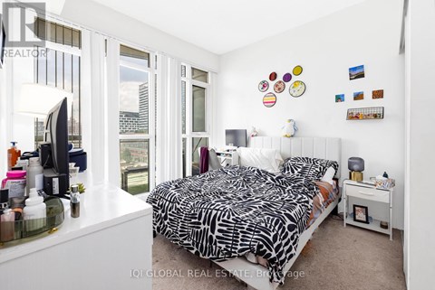A bedroom with a large bed and a window overlooking a cityscape.
