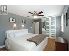 A bedroom with a bed, a ceiling fan, and a nightstand.