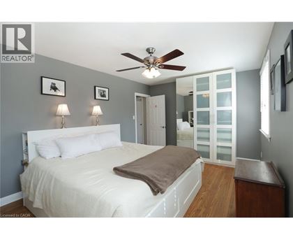 A bedroom with a bed, a ceiling fan, and a nightstand.
