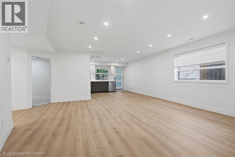 A spacious room with wooden flooring and white walls.