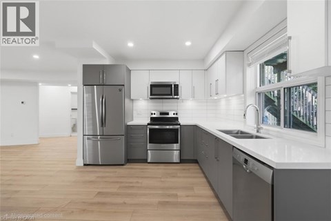 A modern kitchen with stainless steel appliances and wooden flooring.