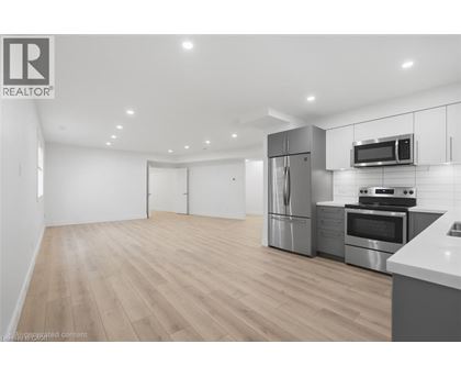 A modern kitchen with stainless steel appliances and wooden flooring.