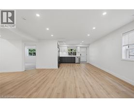 A spacious room with wooden flooring and white walls.