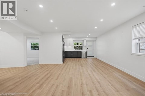 A spacious room with wooden flooring and white walls.