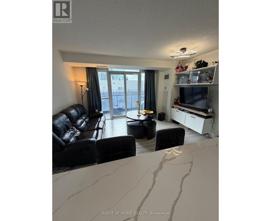 A living room with a black leather couch and a television.
